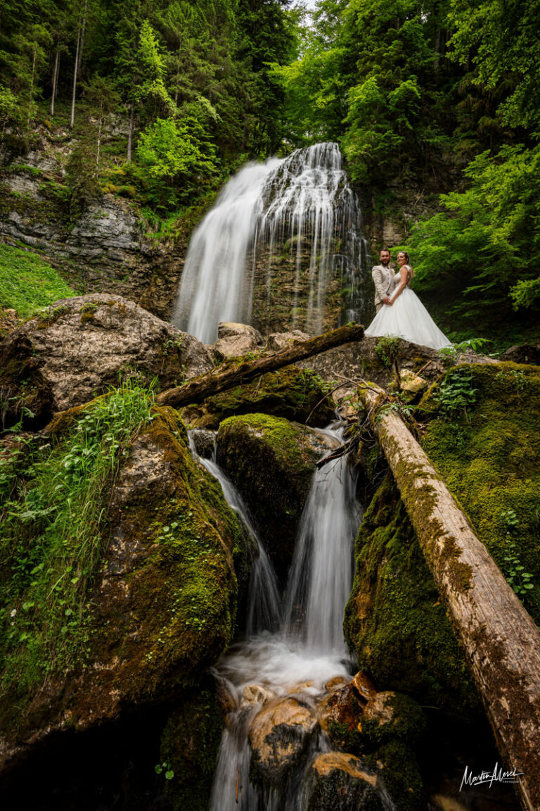 Des mariés au milieu d'une cascade en montagne