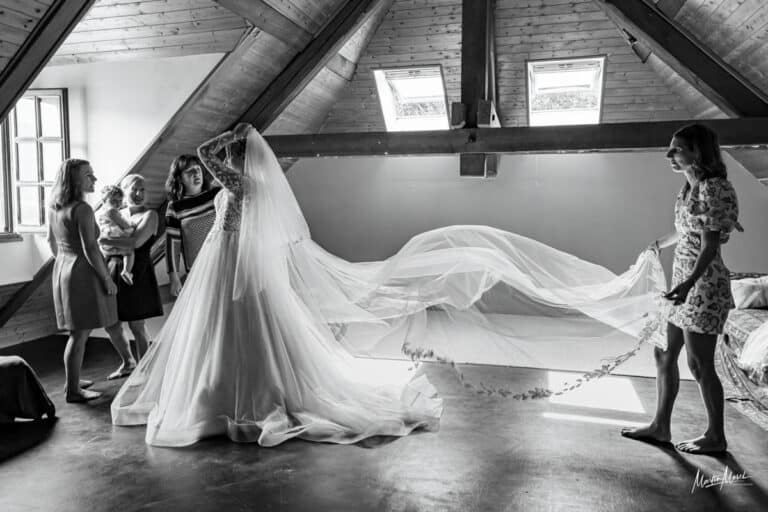 La mariée est prête et sa témoin agite le long voile qui l'accompagnera toute la journée