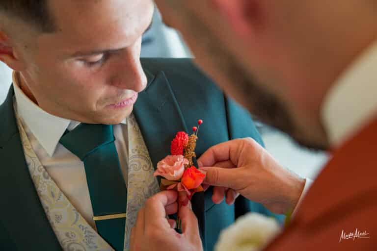 Les mariés se passent réciproquement la boutonnière, délicatement décorée aux couleurs de leur journée