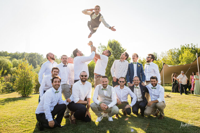 Une photo de groupe où le marié est propulsé dans les airs